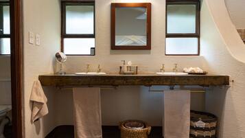 A bathroom with a double sink, two mirrors, and a towel rack.