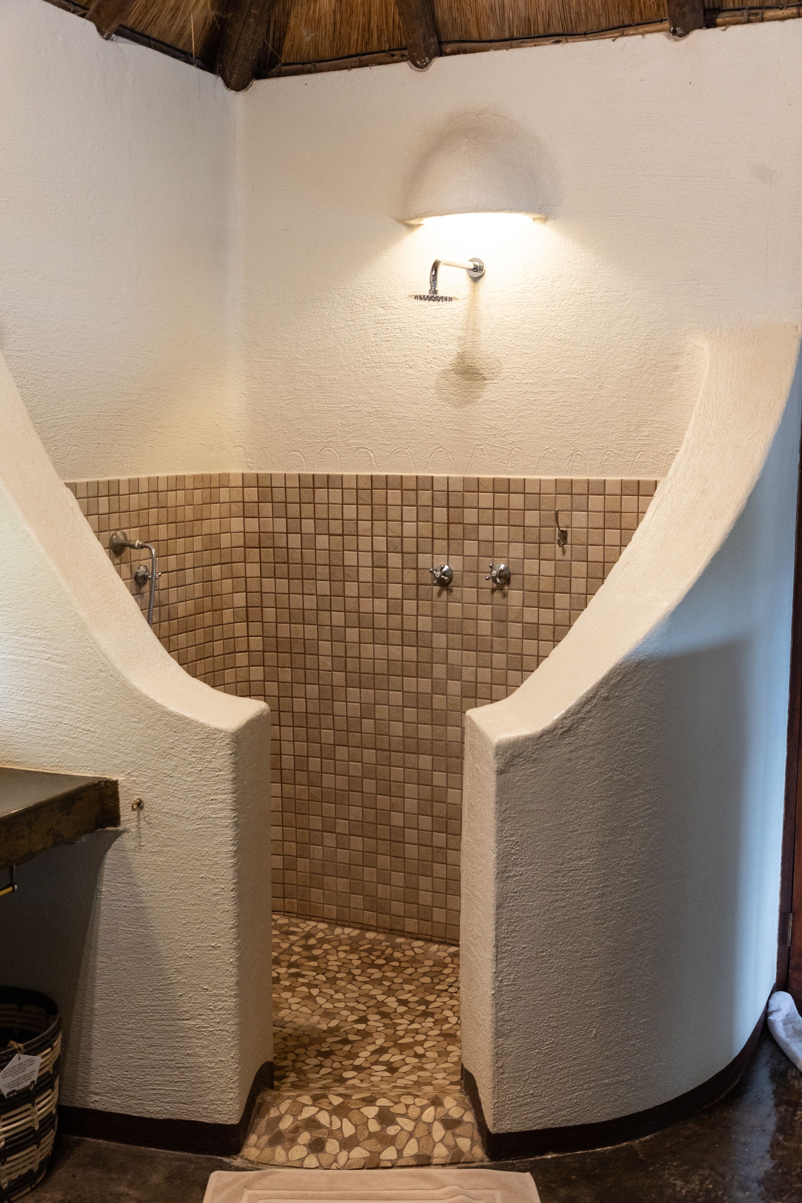 A bathroom with a tiled floor, a shower area, and a sink.
