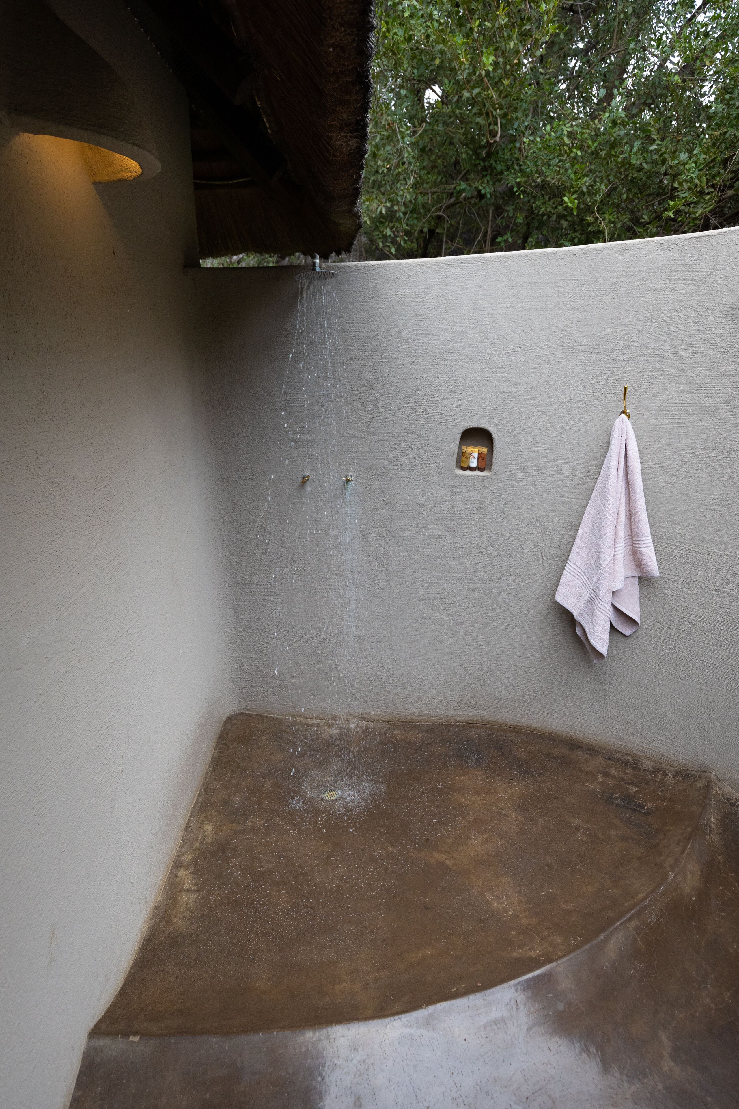 Un baño con un banco de concreto, una toalla colgada en la pared y una ventana pequeña.