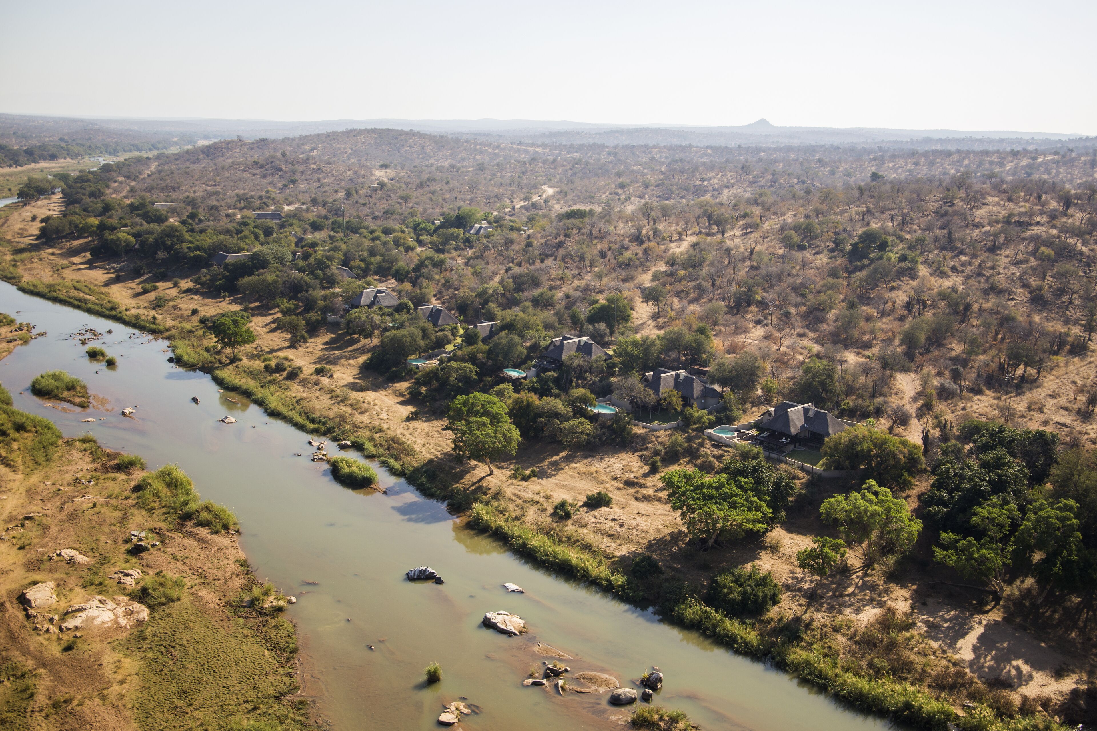 A river flowing through a rural area with scattered houses and sparse vegetation.