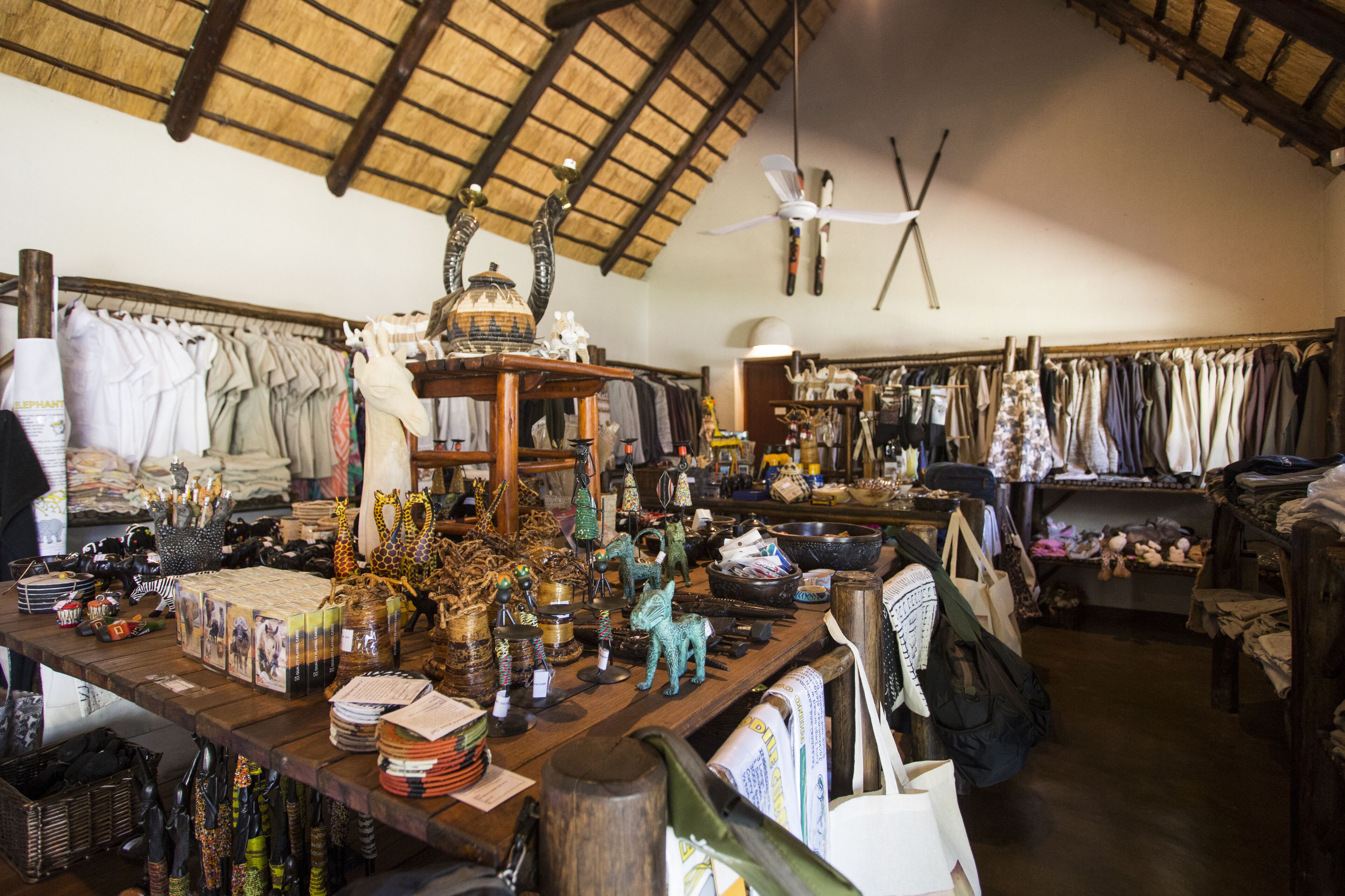 A rustic shop with wooden shelves filled with various items, including clothing and decorative objects.