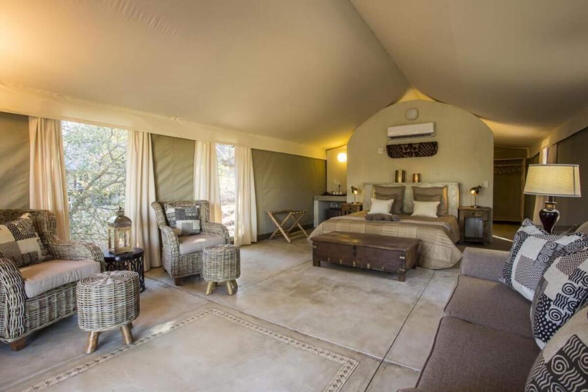 Ein geräumiges Schlafzimmer mit einem großen Bett, zwei Korbstühlen, einer Couch und einem Nachttisch mit Lampe.