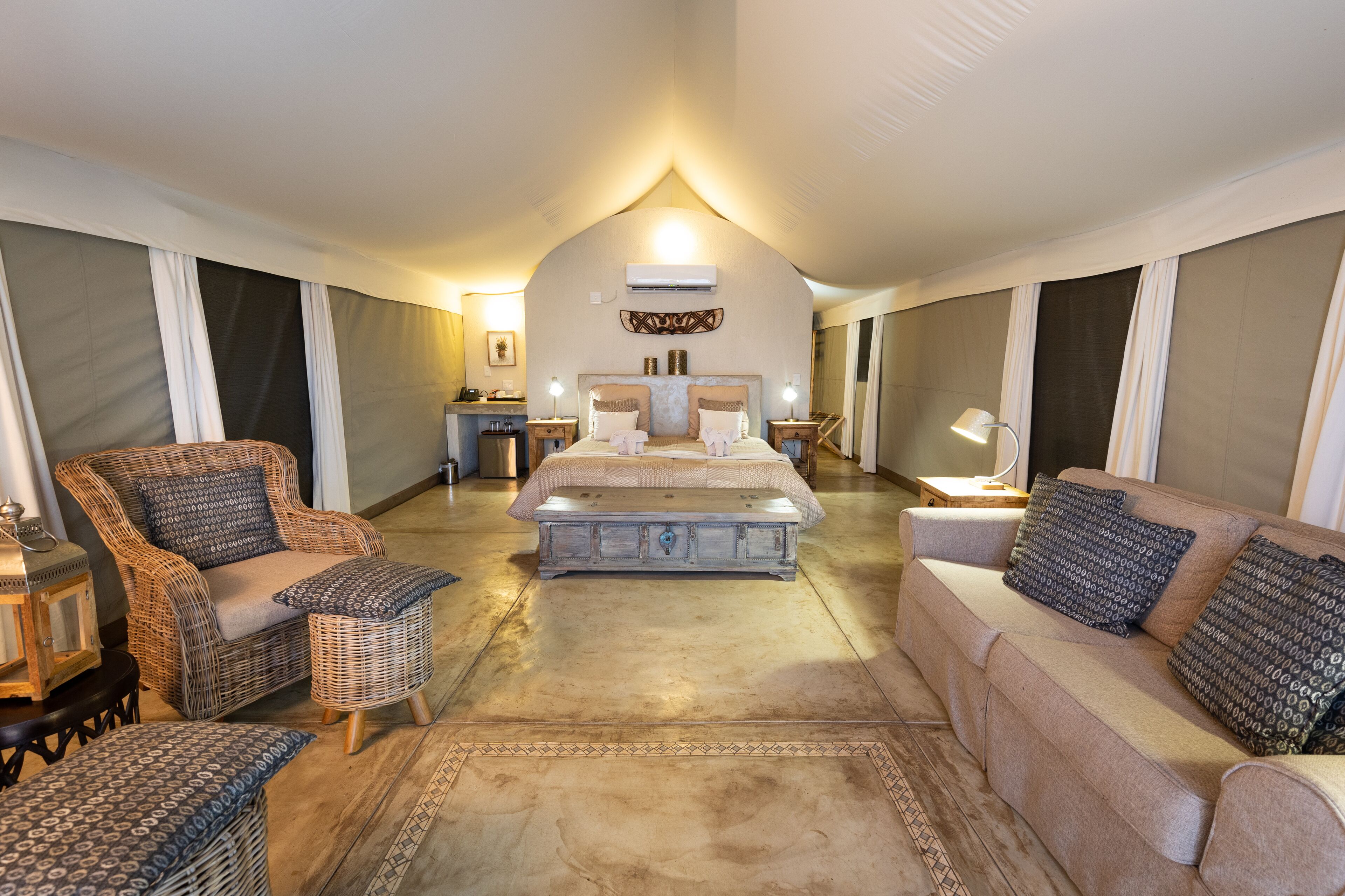 A spacious bedroom with a large bed, two sofas, a small table, and a nightstand.