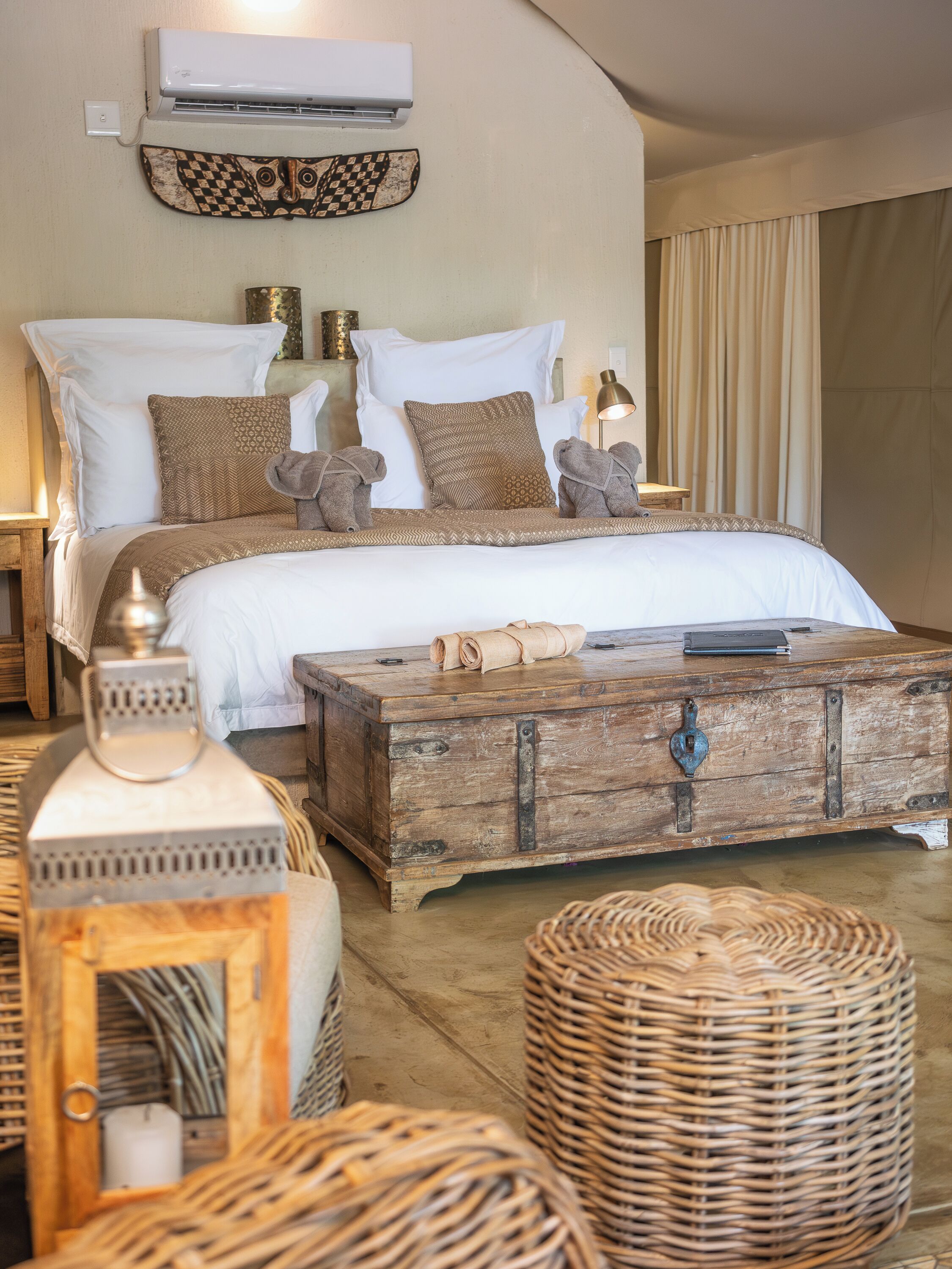 A bedroom with a bed, pillows, a wooden chest, and a woven basket.