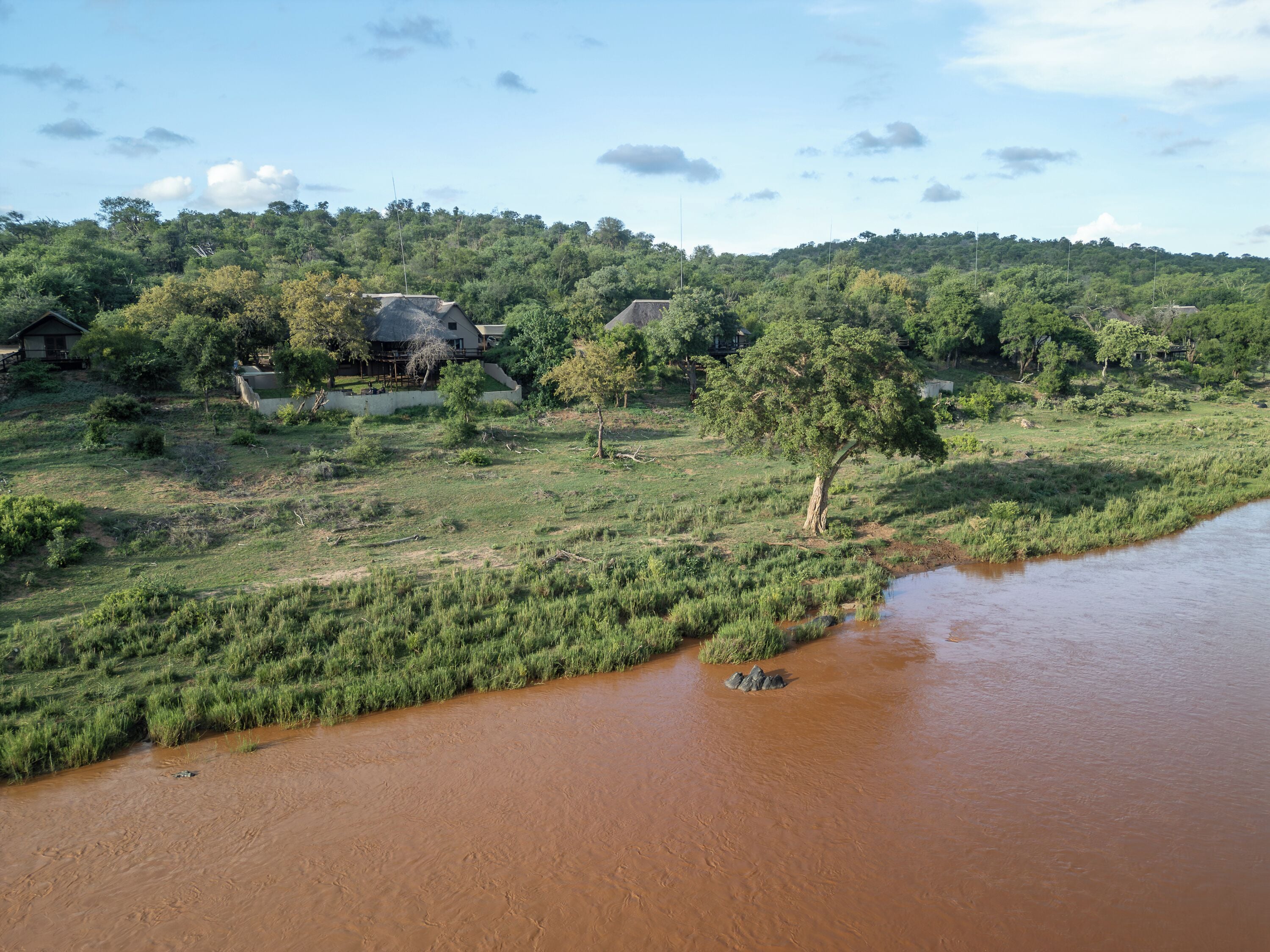 A rural landscape with a river, houses, and dense greenery.
