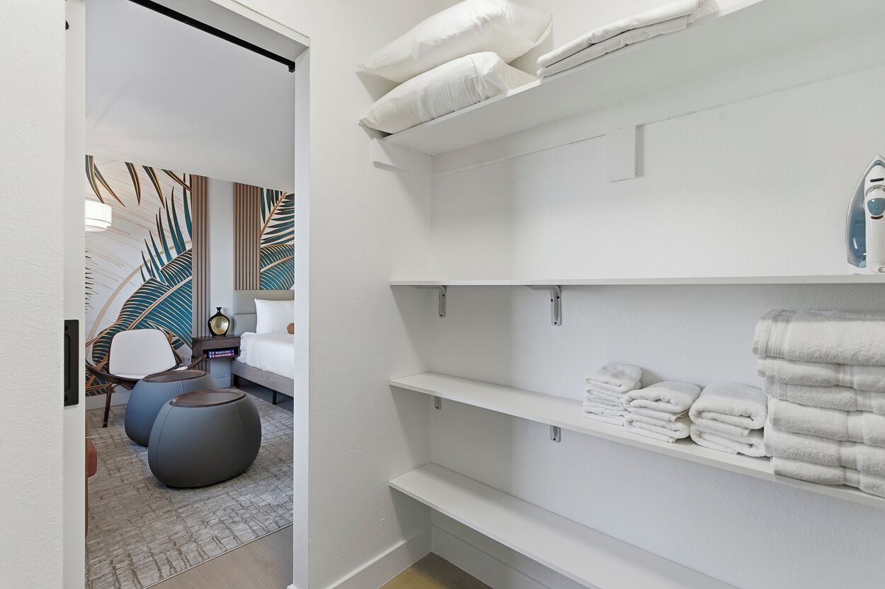A modern bathroom with white shelves, a bed, and a chair.