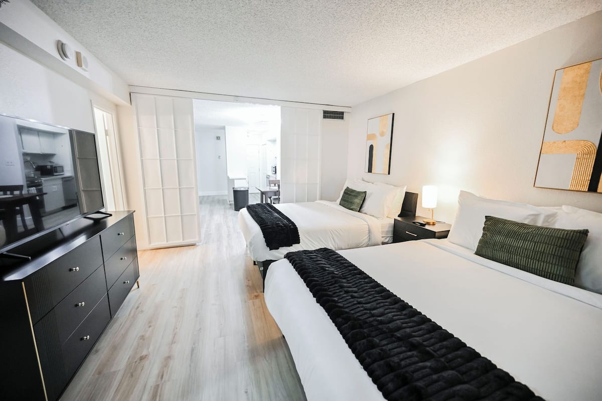 A hotel room with a large bed, a TV, a desk, and a wardrobe.