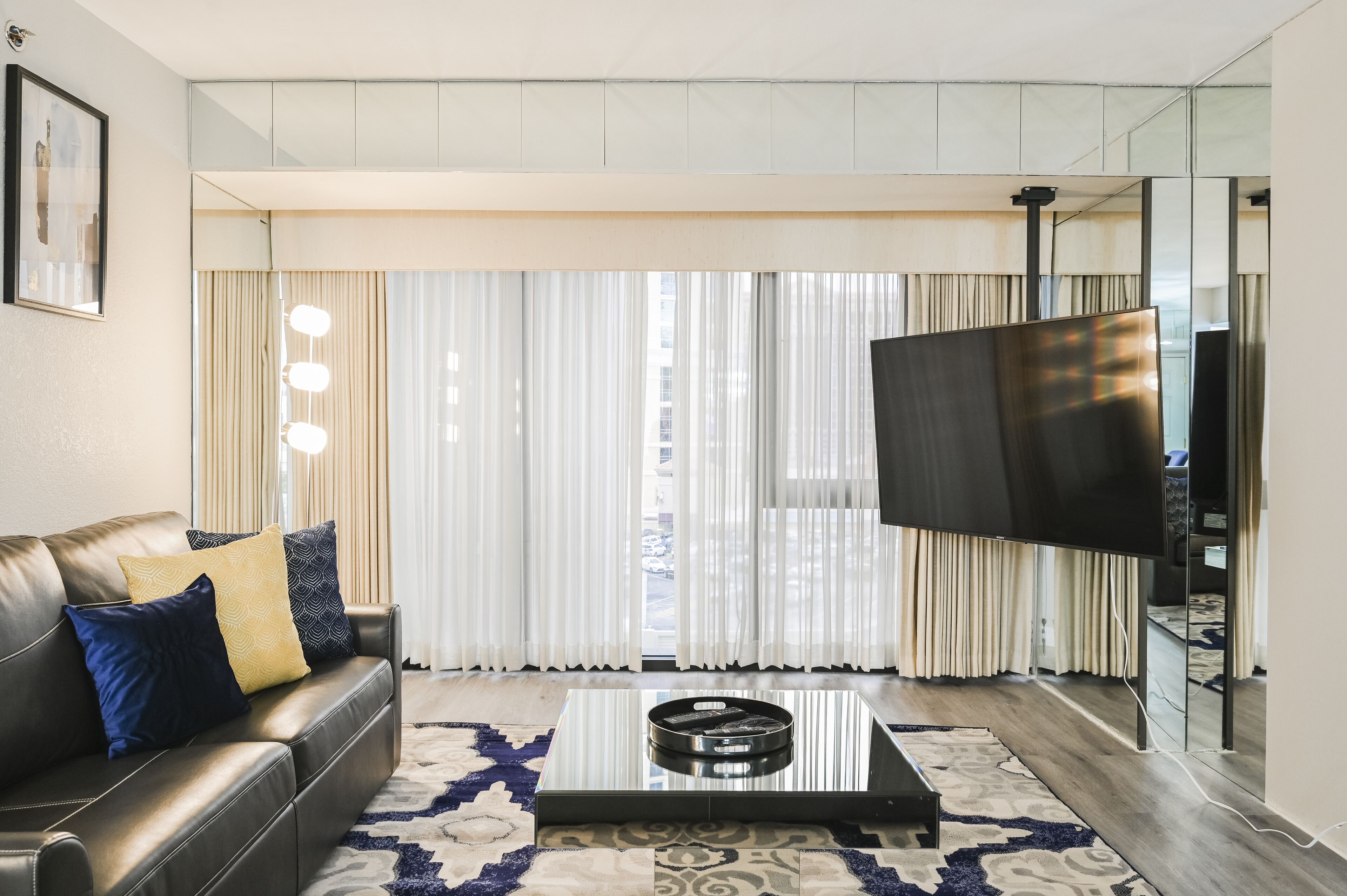 A modern living room with a leather sofa, a coffee table, and a large flat-screen TV.