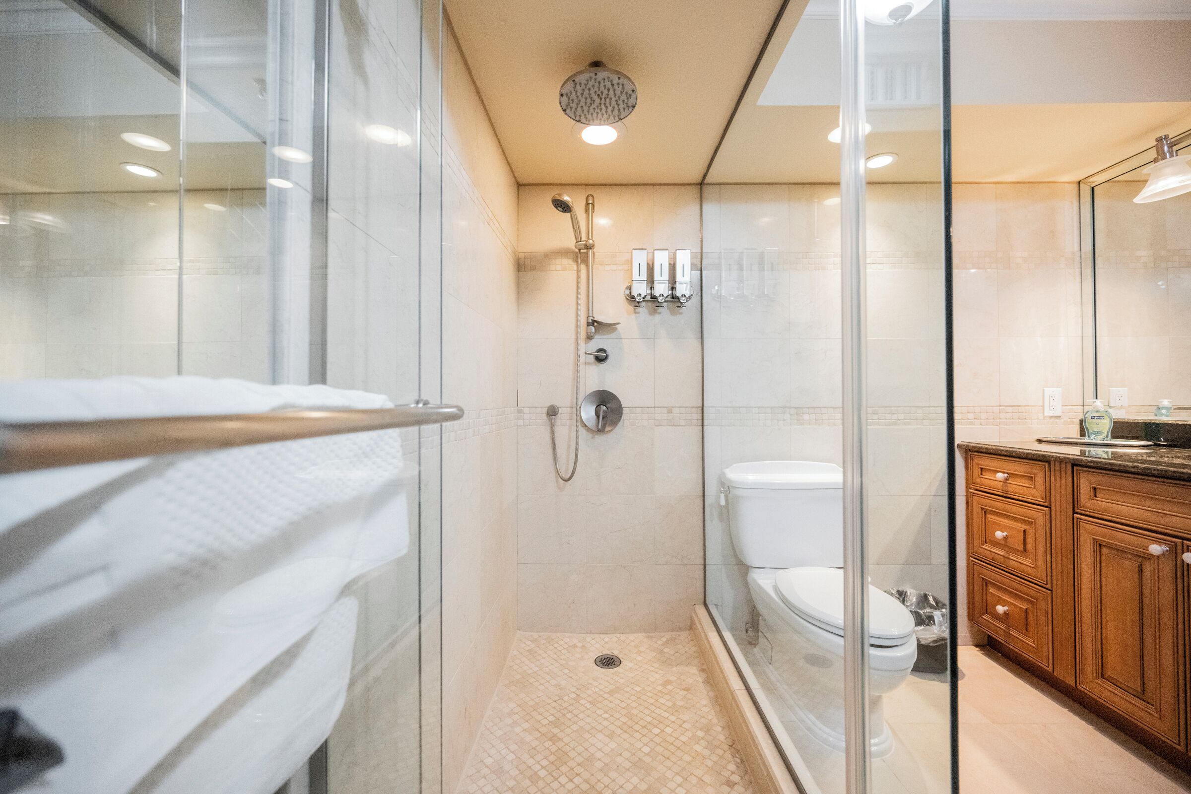 A modern bathroom with a glass shower enclosure, a toilet, and wooden cabinetry.