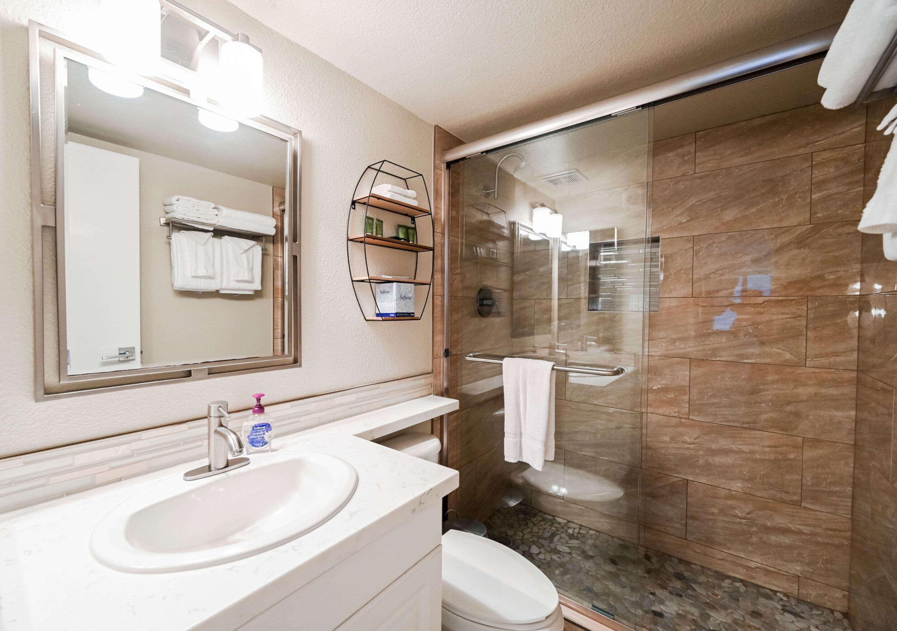 Een badkamer met een wastafel, spiegel en douche.
