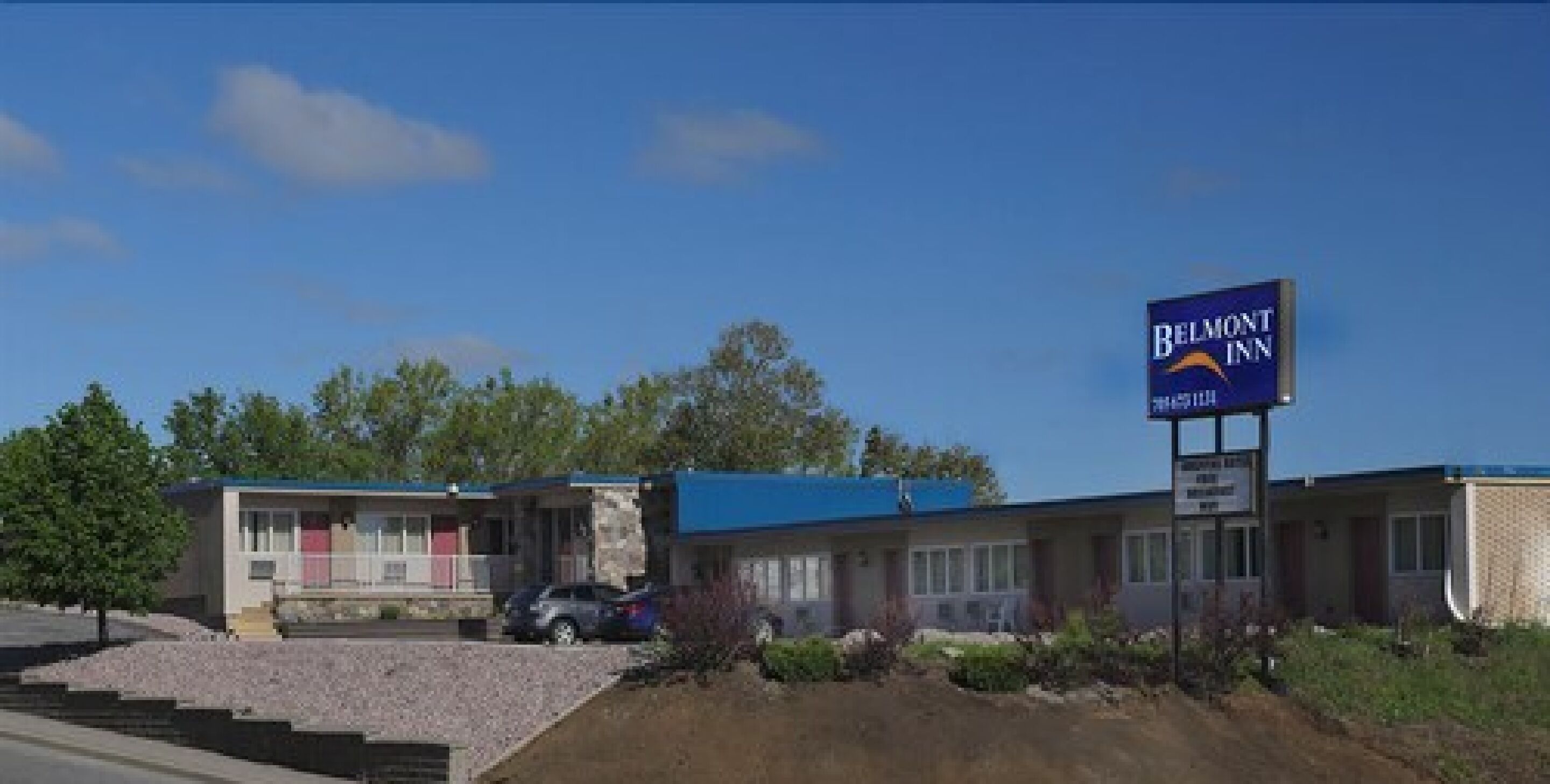 Un Belmont Inn con techo azul, estacionamiento y cielo despejado.