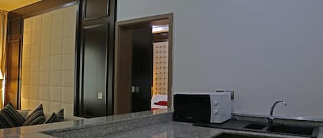 A kitchen with a granite countertop, a microwave, and a sink.