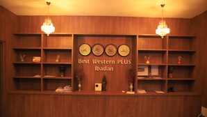 A reception desk with a wooden finish, multiple shelves, and a chandelier. - Best Western Plus By Bayse-LTD (Ibadan)