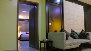 A hotel room with a sofa, a small table, and a bed with a white headboard. - Best Western Plus By Bayse-LTD (Ibadan)
