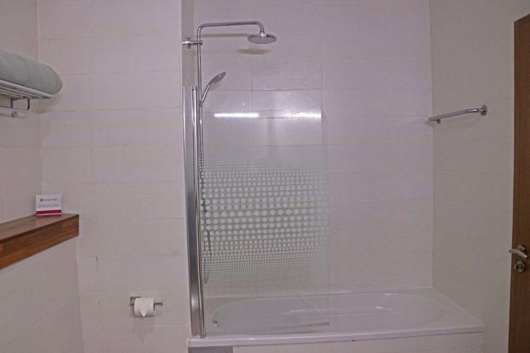 A shower enclosure with a glass door, a handheld showerhead, and a wall-mounted towel rack.