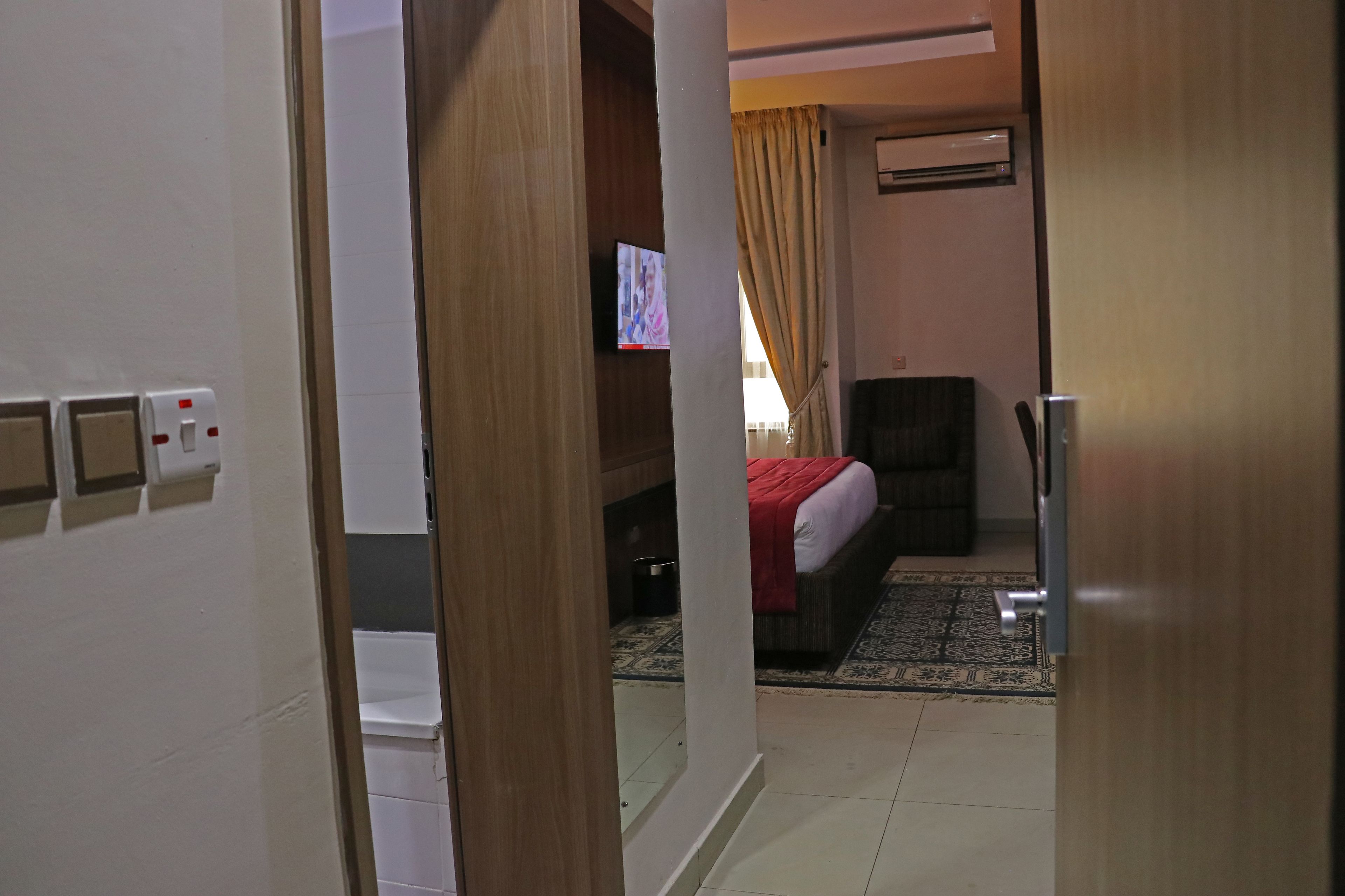 Une chambre d’hôtel avec un lit, une télévision, un bureau et une fenêtre avec des rideaux.
