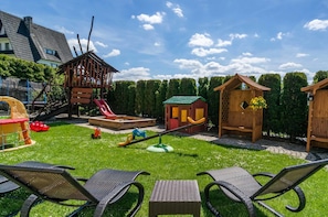 A backyard with a wooden playhouse, a slide, and a swing set. - Willa Roztoka (Bukowina Tatrzanska)
