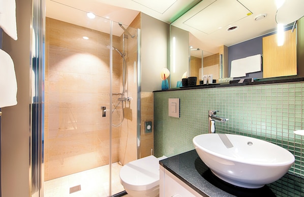 A modern bathroom with a glass-enclosed shower, a white sink, and a tiled backsplash.
