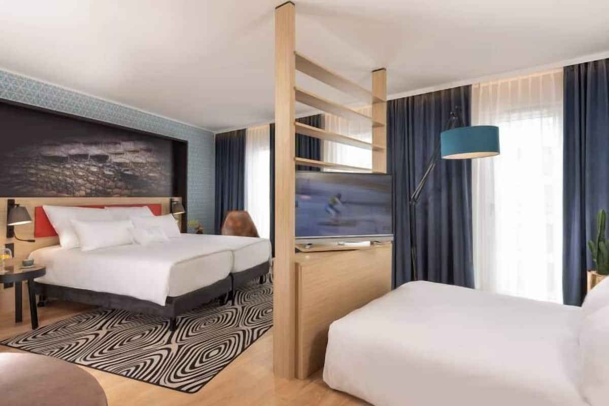 A hotel room with a bed, a desk, a TV, and a lamp.