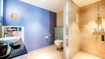 A modern bathroom with a large sink, toilet, and glass-enclosed shower area.