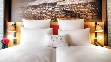 A hotel room with a large bed, two bedside lamps, a red accent wall, and a wall-mounted telephone.