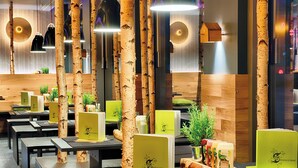 A restaurant with birch tree decor, green menu stands, and a wooden wall. - NYX Hotel Munich by Leonardo Hotels (Munich)