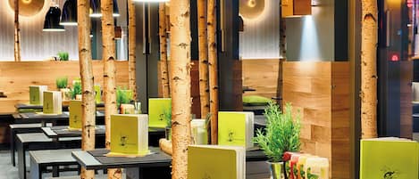 Interior de restaurante con columnas de abedul, mesas con menús y un diseño moderno.