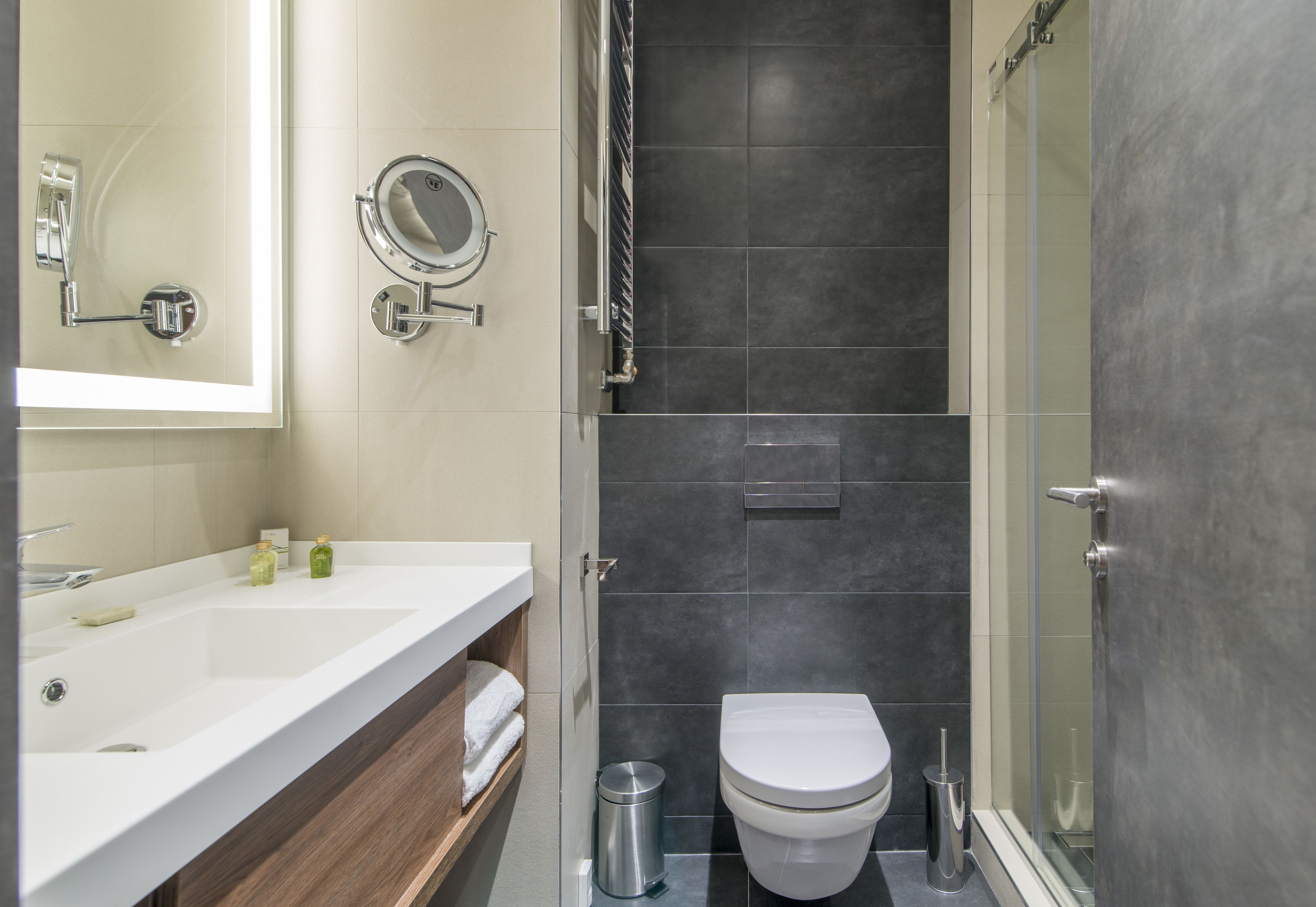 Een moderne badkamer met een witte wasbak, spiegel en toilet.