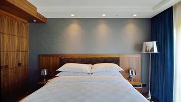 A hotel room with a large bed, wooden headboard, two bedside tables with lamps, and a floor lamp.