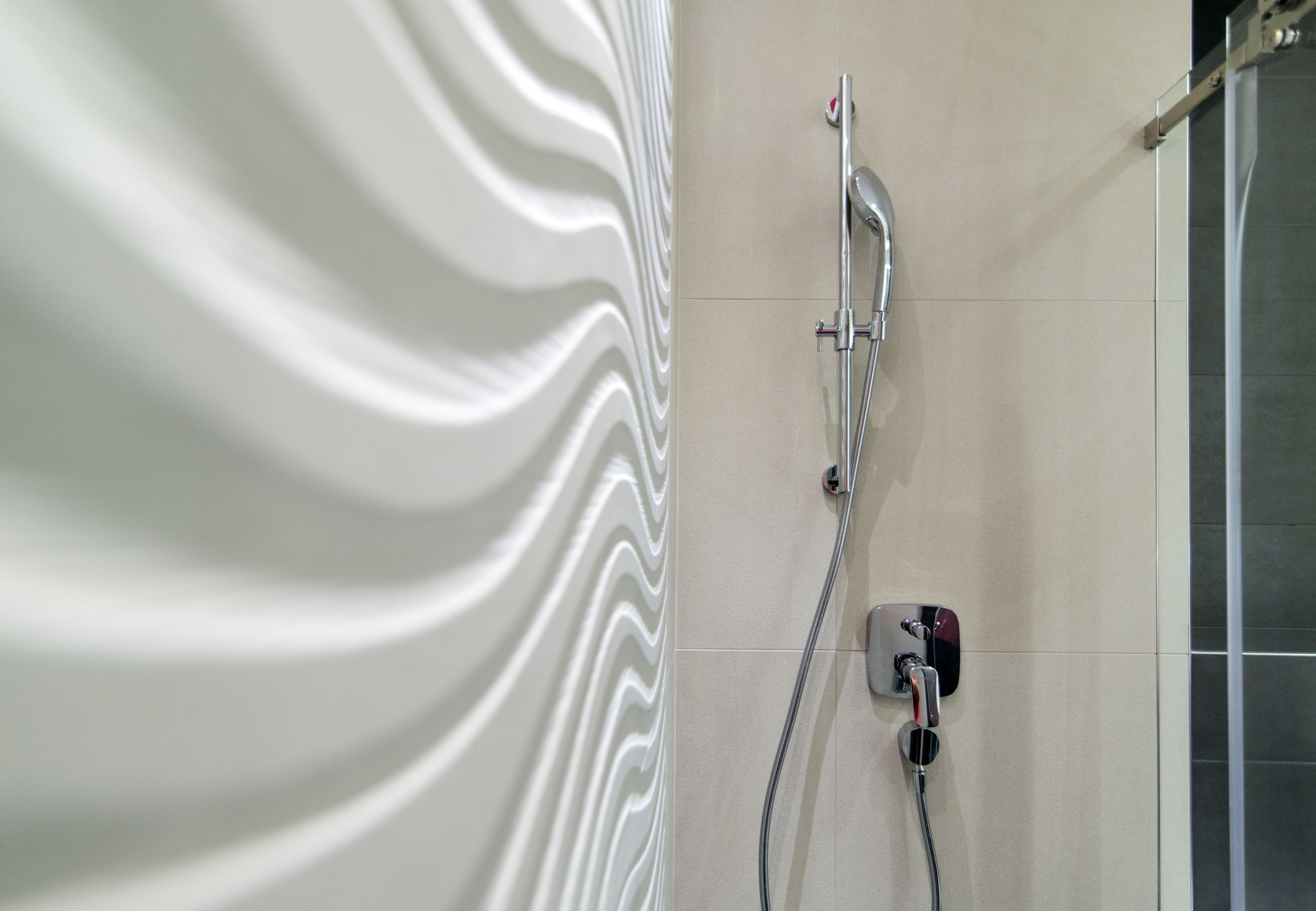 Une douche au design moderne, comprenant un robinet mural et une douchette à main.