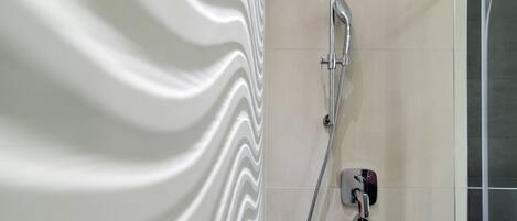 Une douche au design moderne, comprenant un robinet mural et une douchette à main.