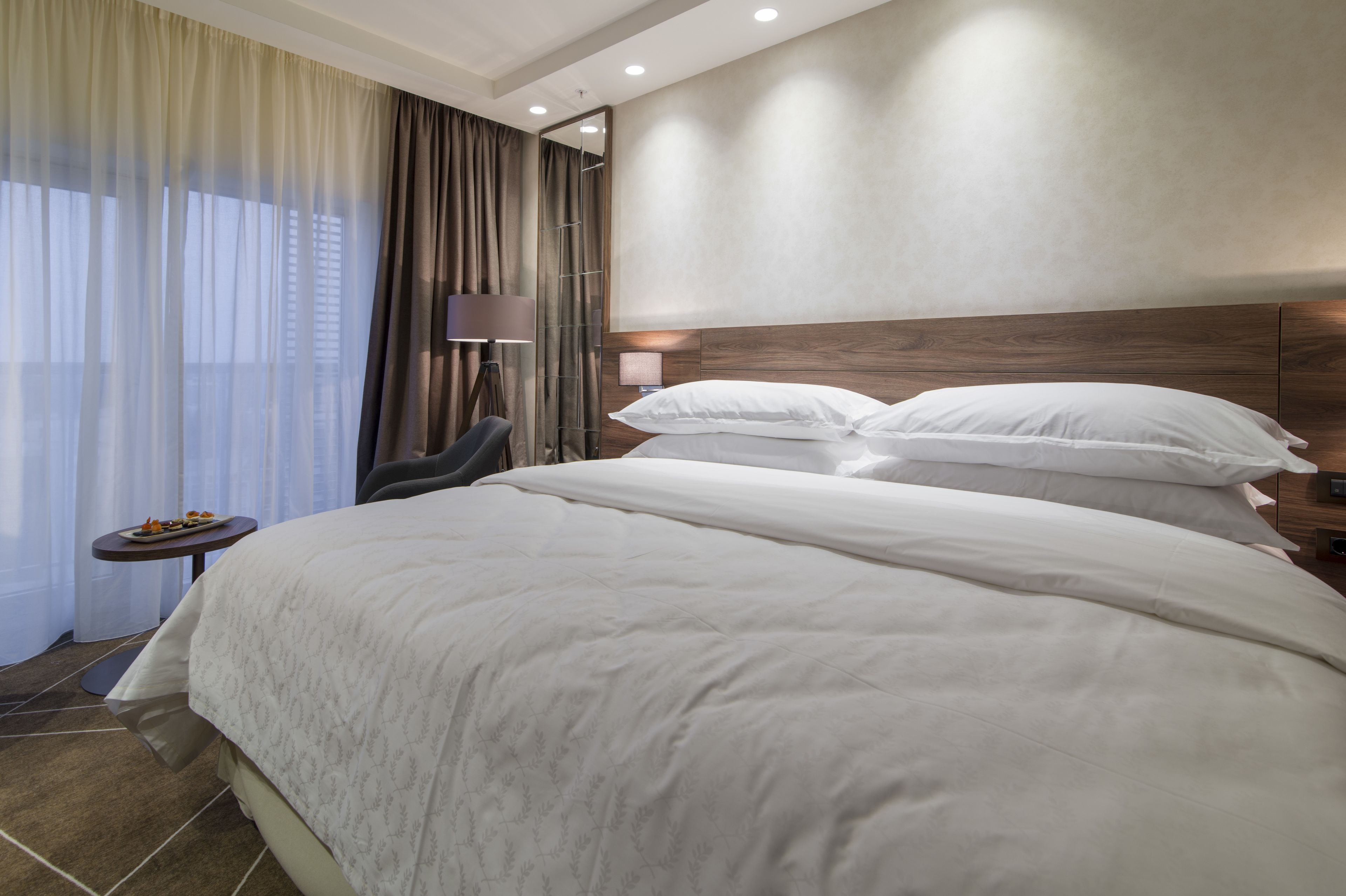 Ein Hotelzimmer mit einem großen Bett, einem kleinen Tisch mit Lampe und einem Sessel.