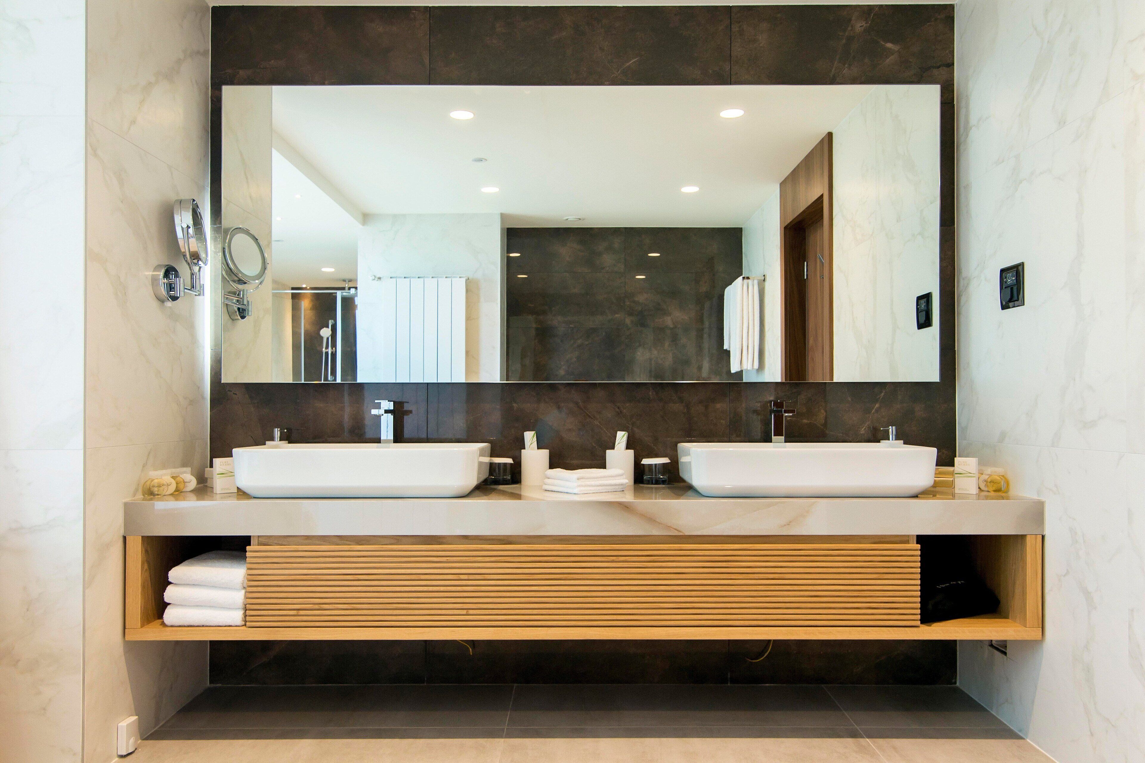 Un baño moderno con dos lavamanos, un espejo grande y un mueble de tocador de madera.