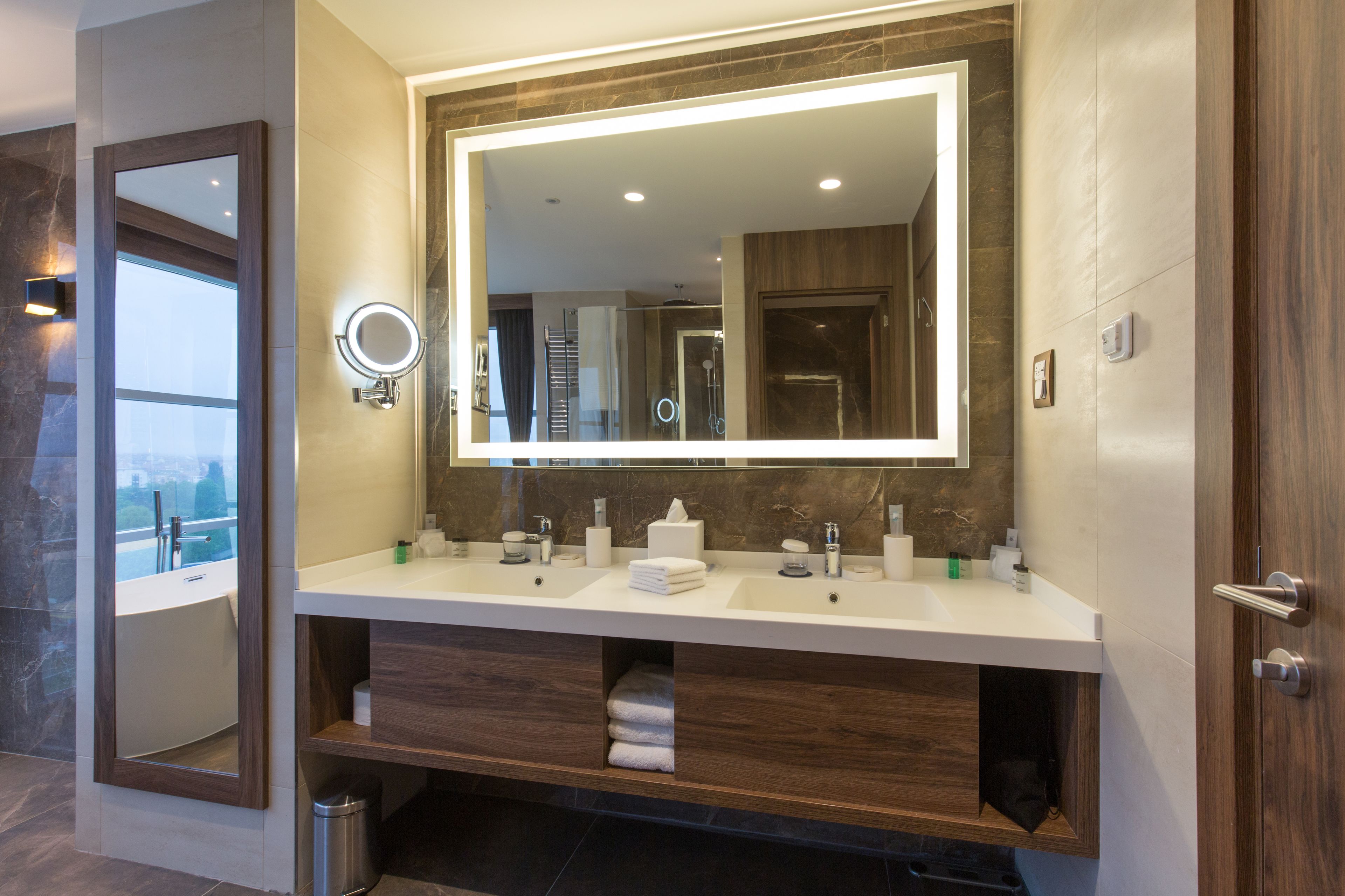 Un bagno moderno con un ampio specchio, due lavabi e un mobile contenitore.