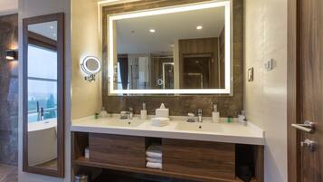 A modern bathroom with a large mirror, two sinks, and a vanity with storage.