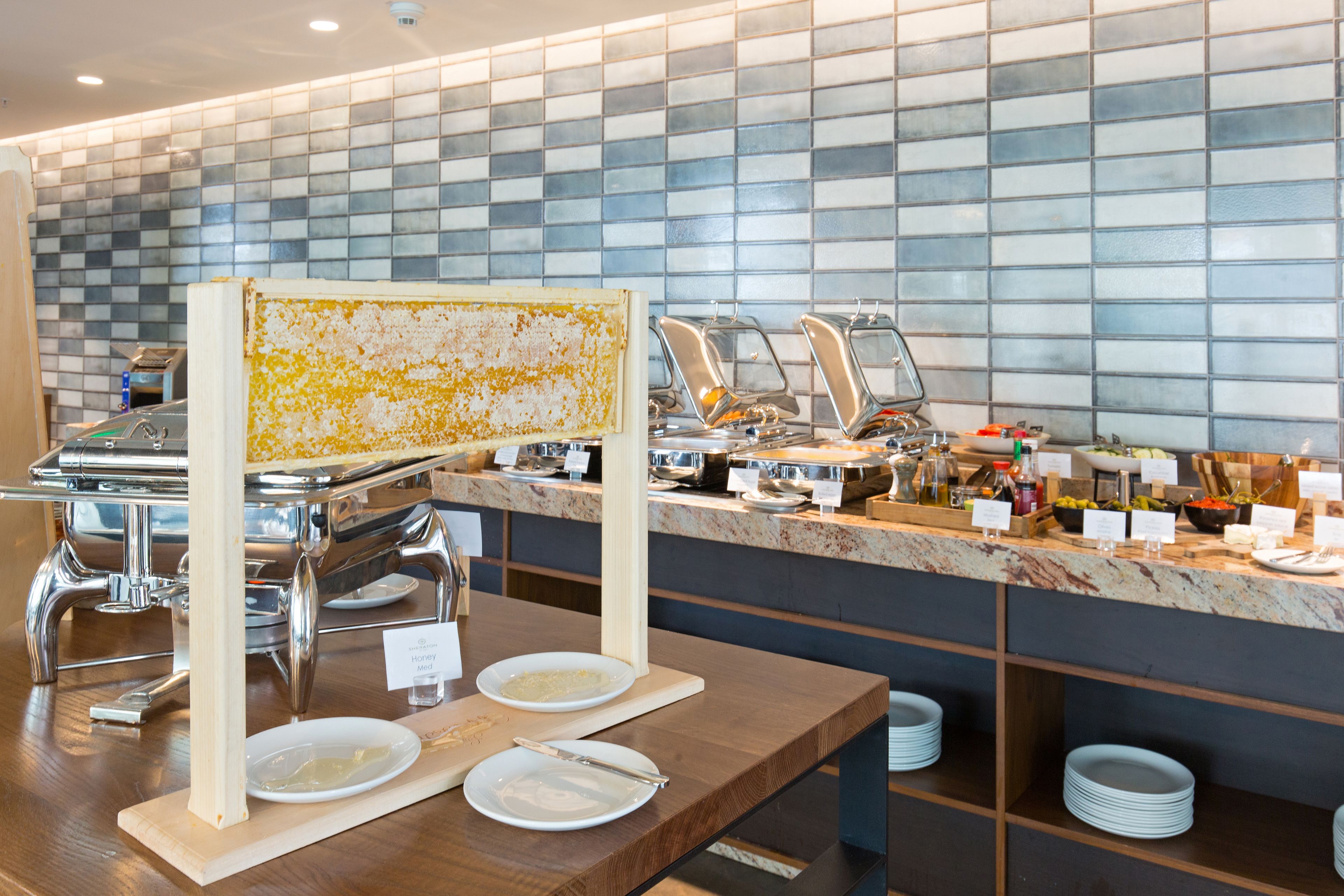 A buffet setup with various food stations and a tiled wall in the background.