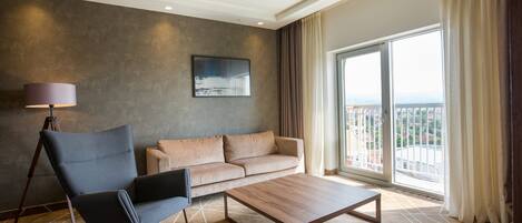A modern living room with a sofa, a chair, a coffee table, and a large window with a view.