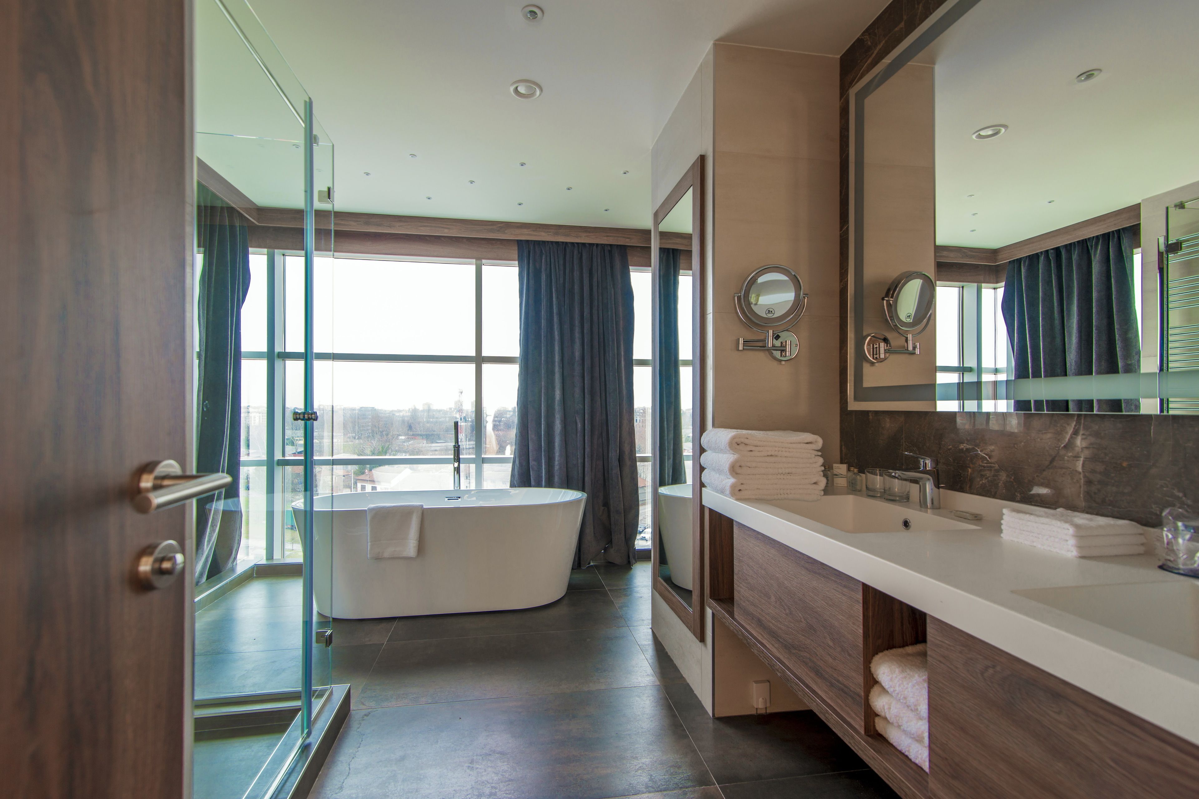 A modern bathroom with a freestanding bathtub, dual sinks, and a large mirror.