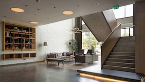 A spacious lobby with a staircase, a seating area, and a bookshelf. - Sheraton Novi Sad (Novi Sad)