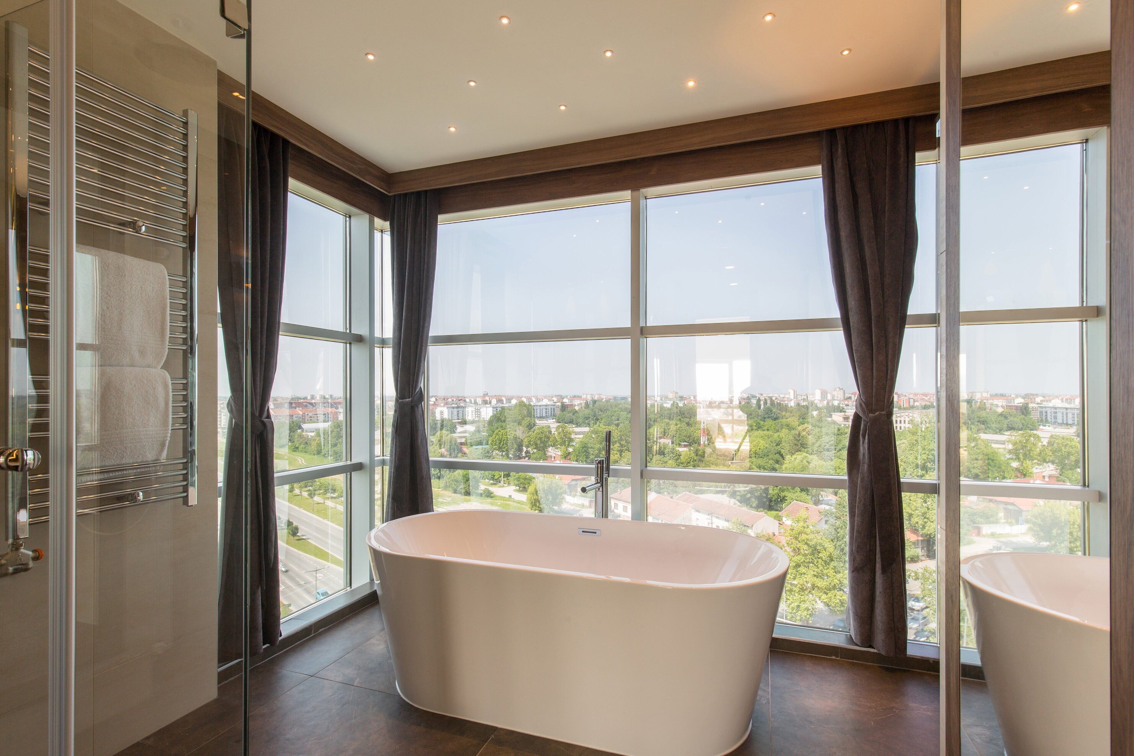 Une salle de bain moderne avec une baignoire sur pieds, de grandes fenêtres et une vue sur le paysage urbain.