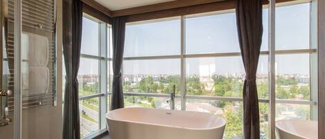 Une salle de bain moderne avec une baignoire sur pieds, de grandes fenêtres et une vue sur le paysage urbain.
