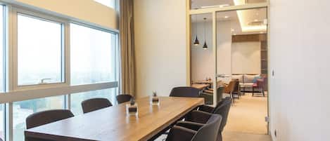 A conference room with a long table, chairs, and large windows.