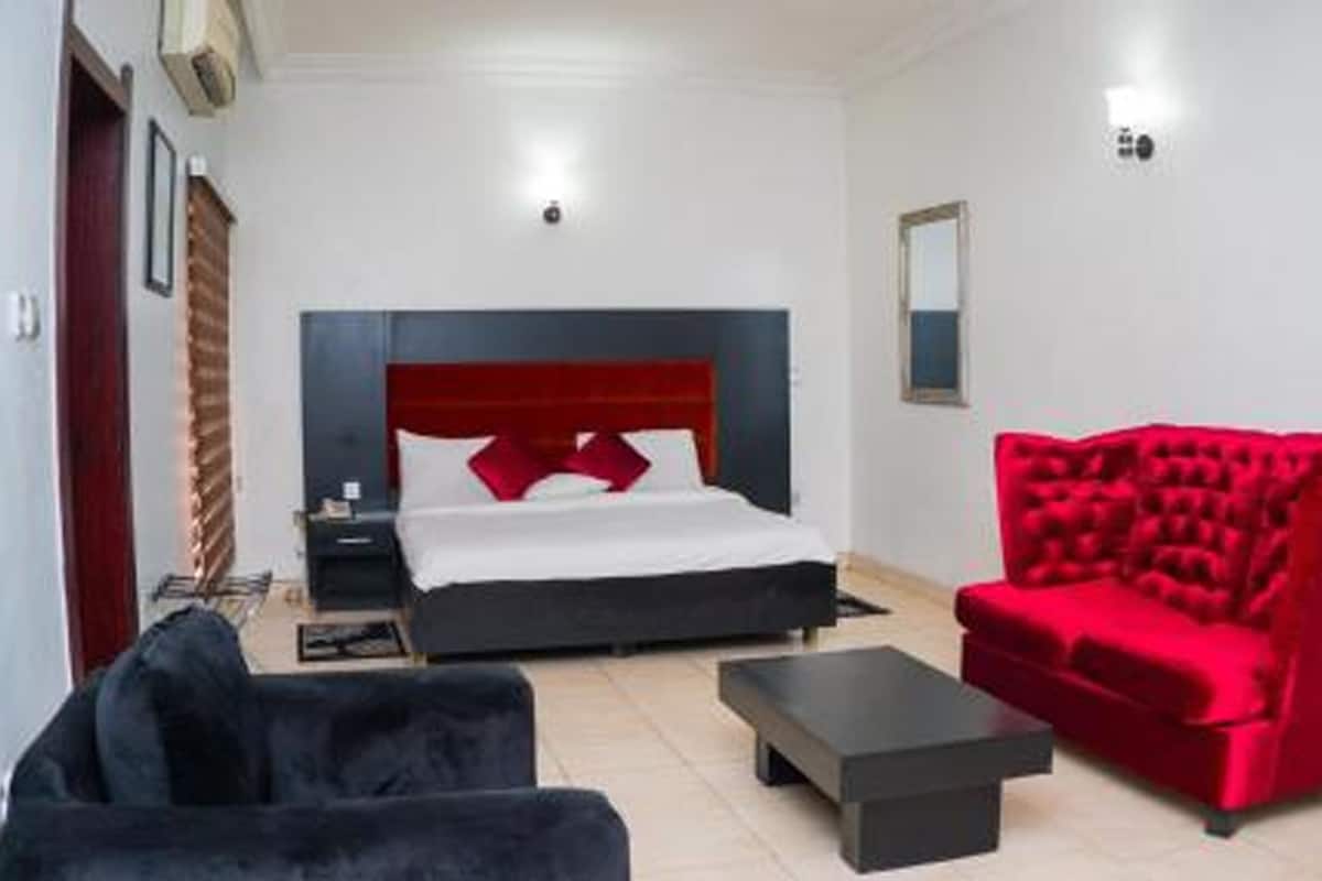 Een hotelkamer met een bed, een rode fauteuil, een zwarte bank en een kleine tafel.