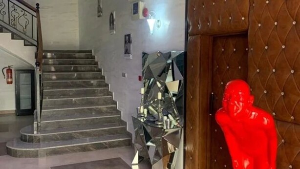 Un vestíbulo con una escalera, una escultura roja y un elemento decorativo espejado.