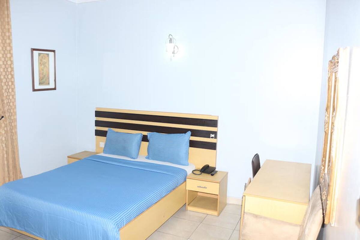 Een slaapkamer met een bed, nachtkastje en bureau.