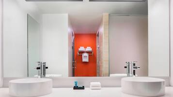 A modern bathroom with two sinks, a large mirror, and a red accent wall.
