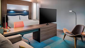 Une chambre d’hôtel moderne équipée d’un lit, d’un bureau, d’une chaise, d’une télévision et d’une lampe.