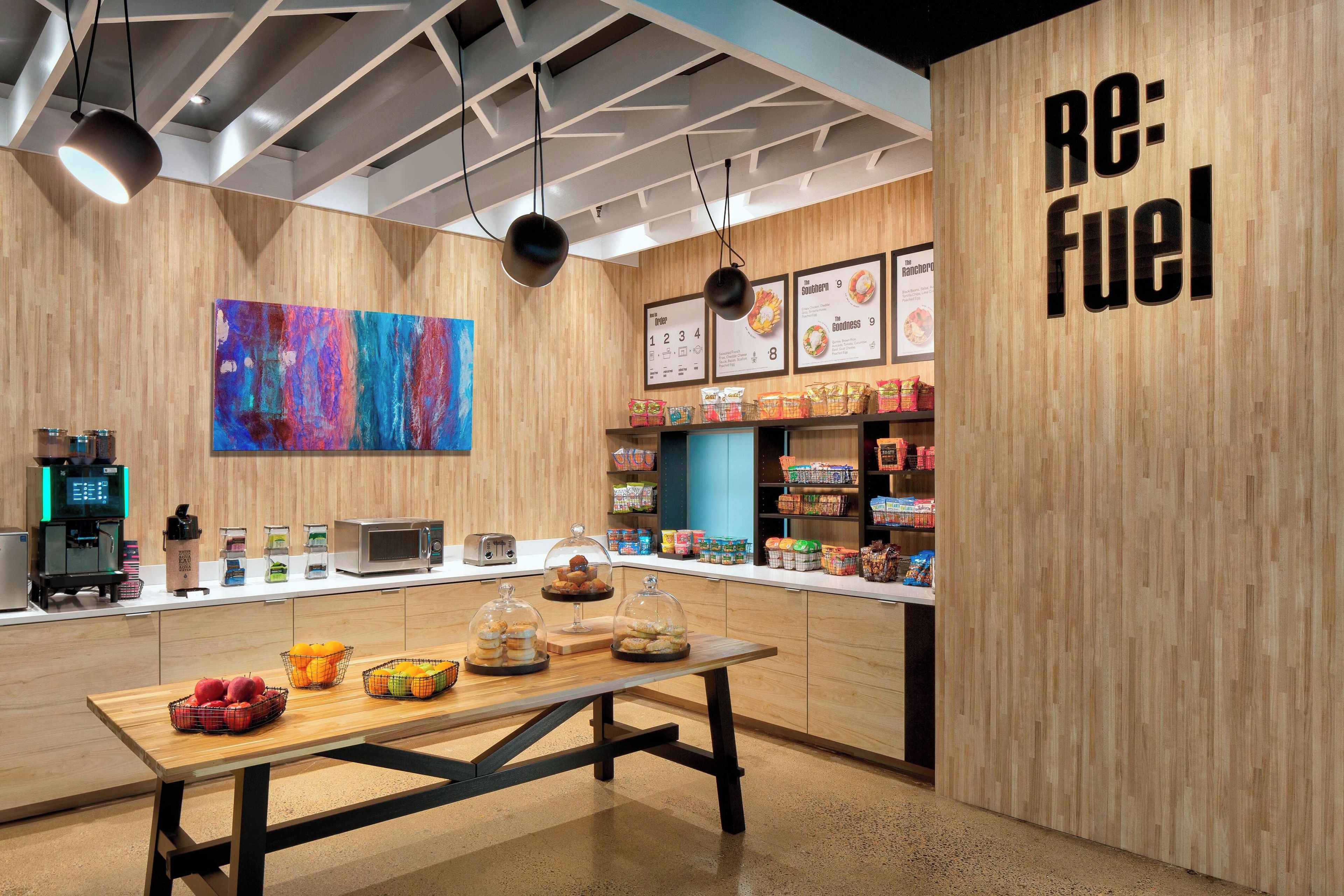 A modern café interior with a wooden theme, a coffee machine, a menu board, and a table with pastries.
