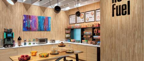A modern café interior with a wooden theme, a coffee machine, a menu board, and a table with pastries.