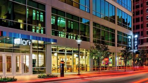 A modern hotel with large glass windows, a well-lit entrance, and a visible restaurant area inside. - Aloft by Marriott Fort Worth Downtown (Fort Worth)